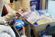 Student grabs period products from a dispenser in a bathroom